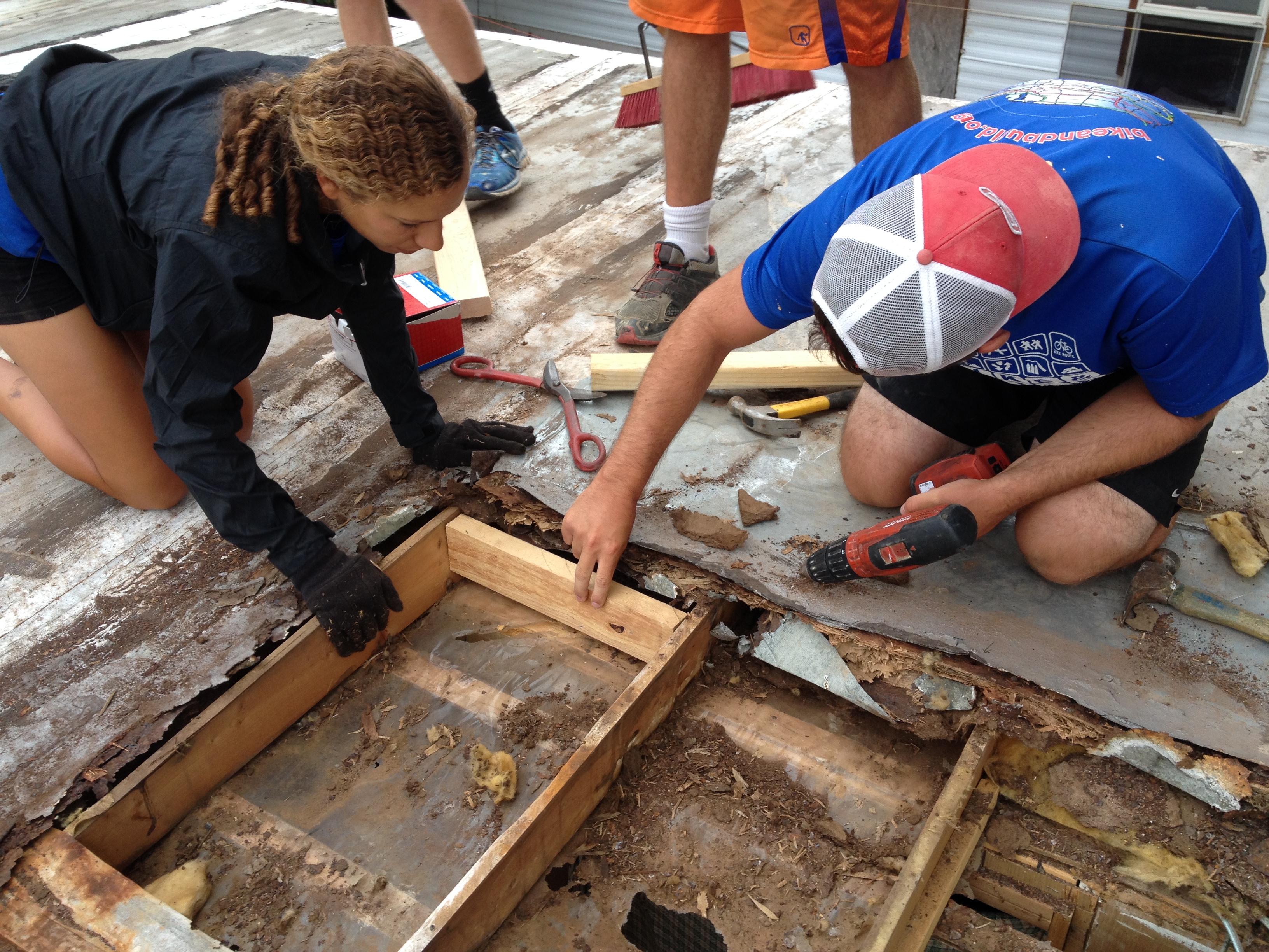 Bike & Build volunteers add structure for a roof patch.